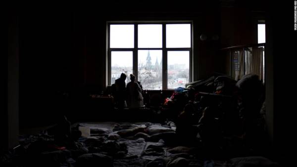 Families, their belongings stacked in piles around them, look out over the entrance to Lviv train station