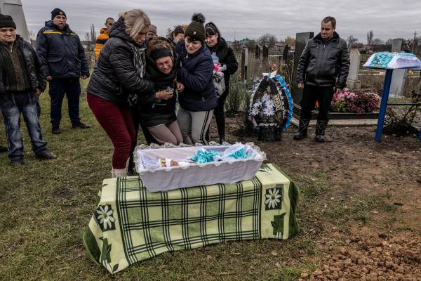 Maria Kamianetska is held by her mother and her sister Lyuba as her son's body lies in a tiny coffin